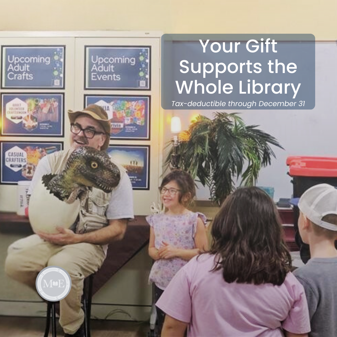 A group of children watch a large dinosaur egg puppet during a Dino Dimensions program at the library. One girl smiles excitedly in the foreground, while other children look on with curiosity and delight.